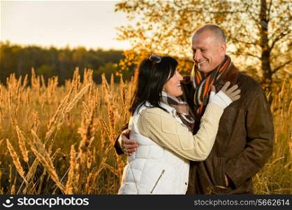 Couple in love hugging in autumn sunset countryside looking each other