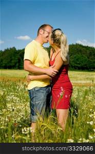 Couple in love kissing each other, standing in a field with wild flowers