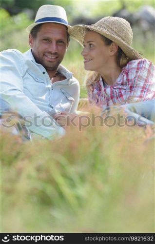 couple in love laying on grass and looking at camera