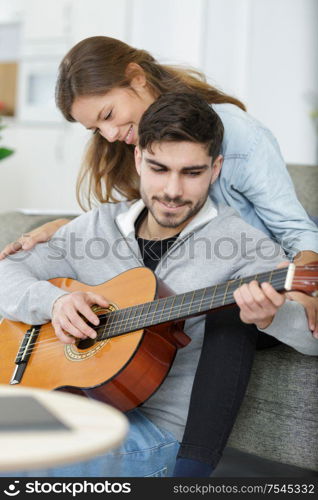 couple in love playing acoustic guitar in the home