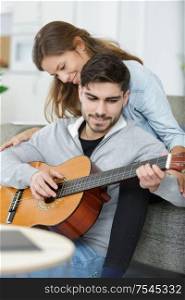 couple in love playing acoustic guitar in the home