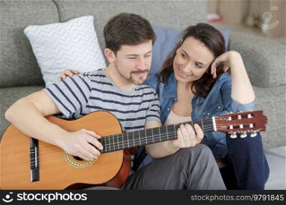 couple in love playing guitar in living room