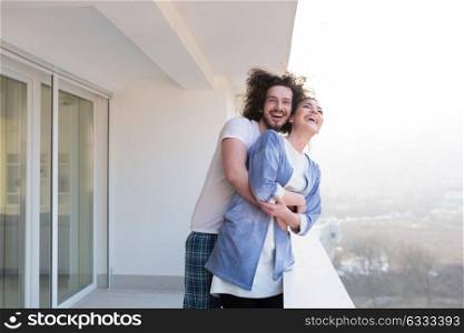 Couple in love sharing emotions and happiness while hugging on the balcony at home