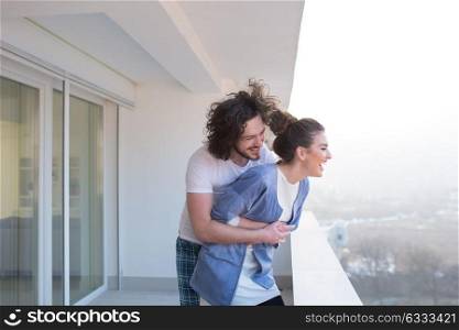 Couple in love sharing emotions and happiness while hugging on the balcony at home