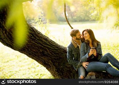 Couple in love sitting on a tree in autumn park