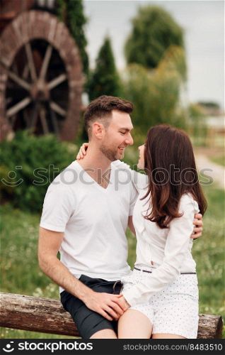 Couple in love walks near a large wooden mill on summer day. man and woman are having fun outdoors. Couple in love walks near a large wooden mill on summer day. man and woman are having fun outdoors.