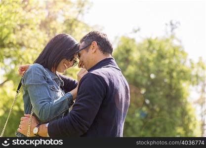 Couple in park face to face hugging and smiling