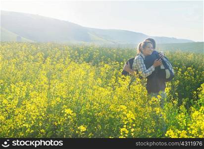 Couple in rapeseed field hugging