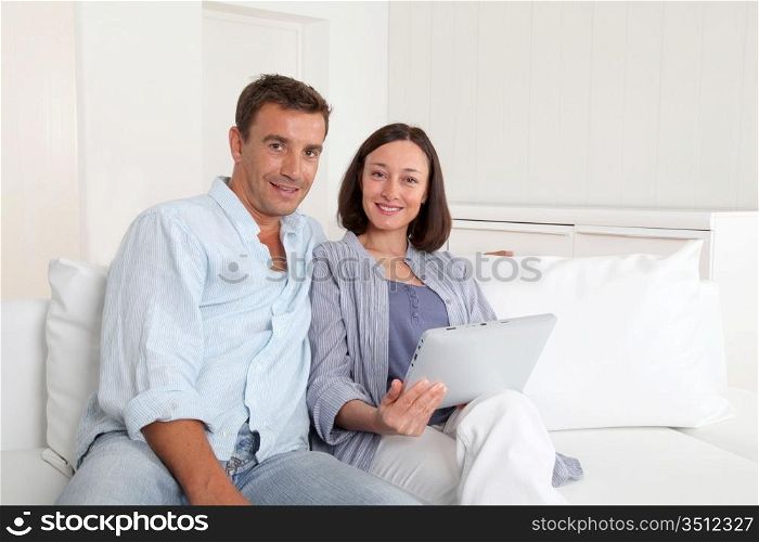 Couple in sofa using electronic tablet