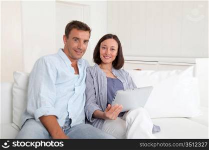 Couple in sofa using electronic tablet