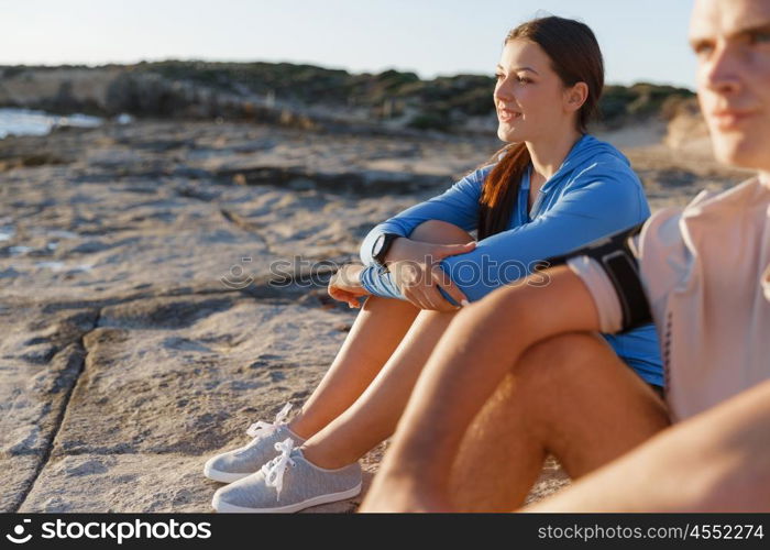 Couple in sport wear on beach. Young coulpe in sport wear sitting on beach