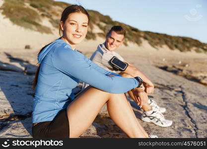 Couple in sport wear on beach. Young coulpe in sport wear sitting on beach