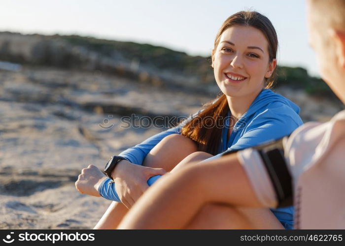 Couple in sport wear on beach. Young coulpe in sport wear sitting on beach