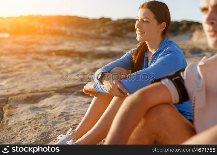 Couple in sport wear on beach. Young coulpe in sport wear sitting on beach