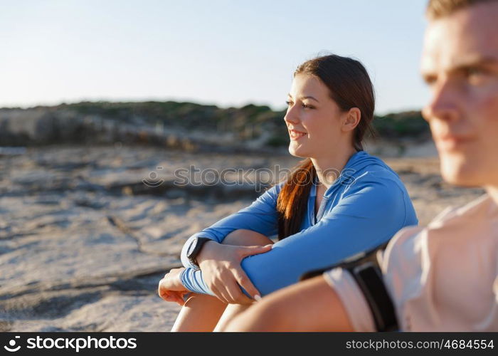 Couple in sport wear on beach. Young coulpe in sport wear sitting on beach