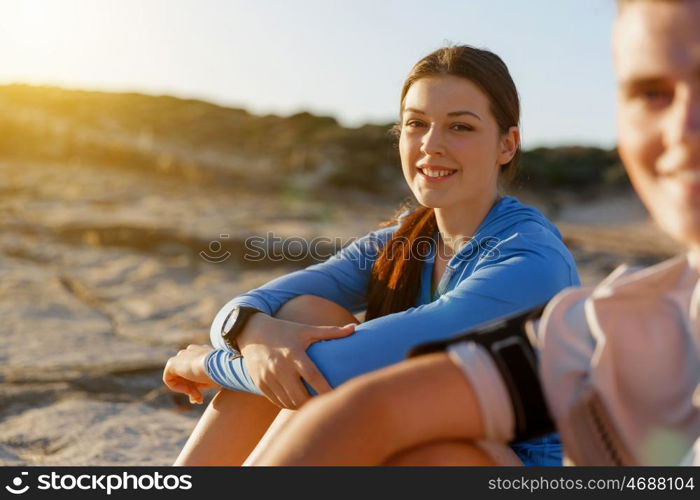 Couple in sport wear on beach. Young coulpe in sport wear sitting on beach