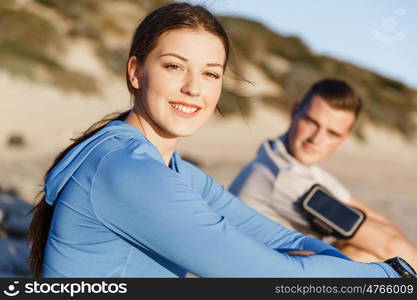 Couple in sport wear on beach. Young coulpe in sport wear sitting on beach