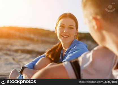 Couple in sport wear on beach. Young coulpe in sport wear sitting on beach