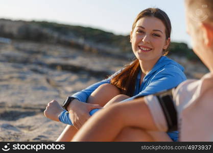 Couple in sport wear on beach. Young coulpe in sport wear sitting on beach