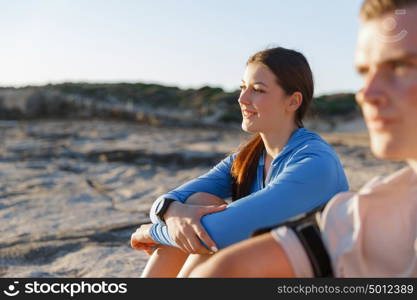 Couple in sport wear on beach. Young coulpe in sport wear sitting on beach