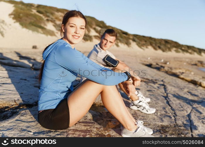 Couple in sport wear on beach. Young coulpe in sport wear sitting on beach