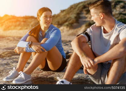 Couple in sport wear on beach. Young coulpe in sport wear sitting on beach