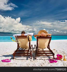 Couple in sun beds on a tropical beach at Maldives