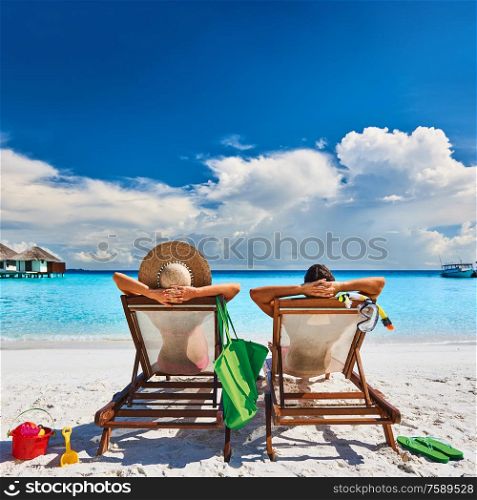 Couple in sun beds on a tropical beach at Maldives