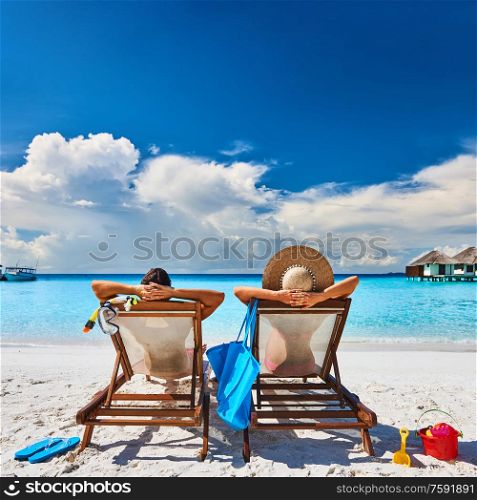Couple in sun beds on a tropical beach at Maldives