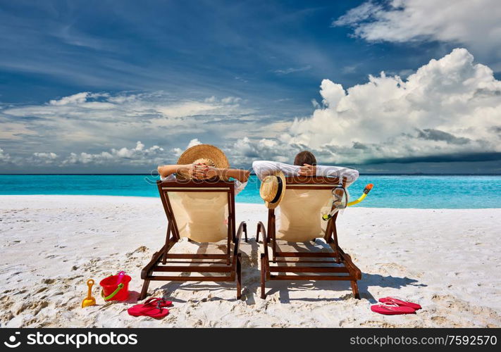 Couple in sun beds on a tropical beach at Maldives