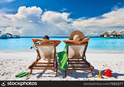 Couple in sun beds on a tropical beach at Maldives