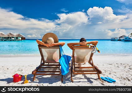 Couple in sun beds on a tropical beach at Maldives