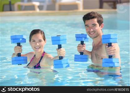 Couple in swimming pool holding floats