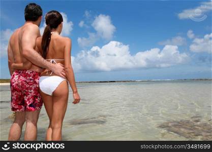 Couple in swimsuit standing by a lagoon