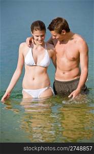 Couple in swimwear enjoy water and sun in summer, standing in sea