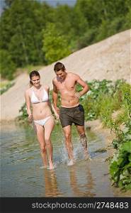 Couple in swimwear jogging at lakeside, enjoy water and sun