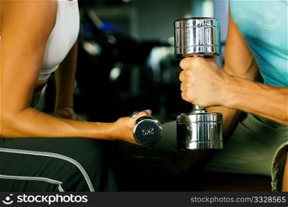 couple in the gym having a workout with dumbbells