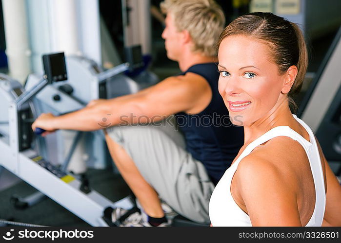 Couple in the gym working out using a rowing machine