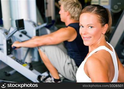 Couple in the gym working out using a rowing machine