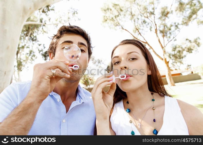 Couple in the park. Happy young couple in the park blowing bubbles