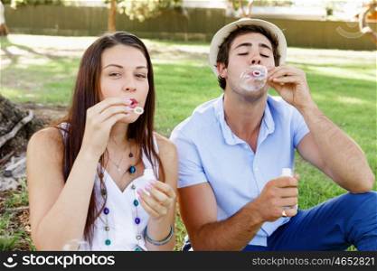 Couple in the park. Happy young couple in the park blowing bubbles
