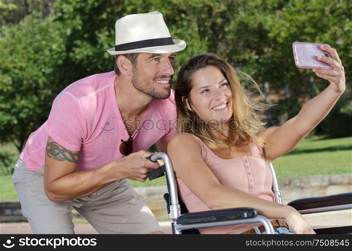 couple in the park taking selfie woman in wheelchair