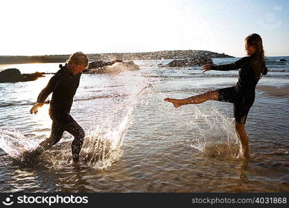 Couple in wetsuits splashing