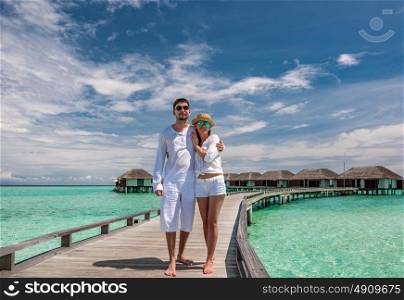 Couple in white on a tropical beach jetty at Maldives