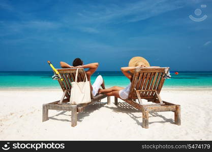 Couple in white relax on a tropical beach at Maldives