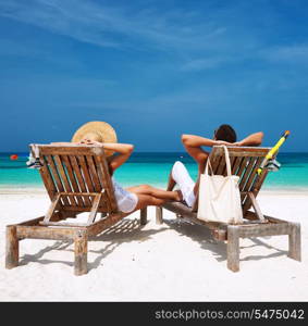 Couple in white relax on a tropical beach at Maldives