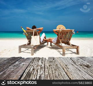 Couple in white relax on a tropical beach at Maldives