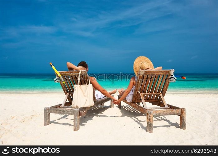 Couple in white relax on a tropical beach at Maldives