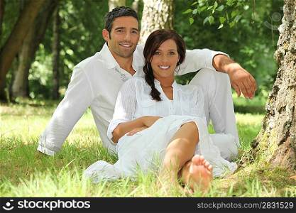 Couple in white sitting on the grass