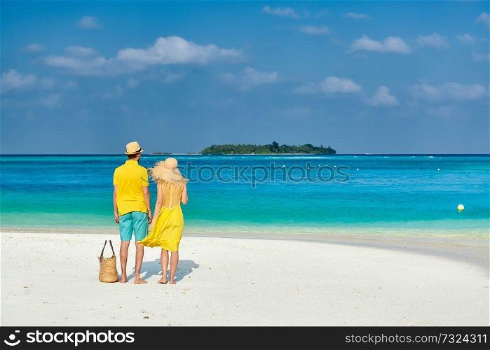 Couple in yellow on tropical beach. Summer vacation at Maldives.